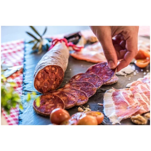 iberian bellota chorizo being placed on a charcuterie board
