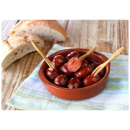 Small spicy chorizos cooked and displayed in a dish with forks and bread