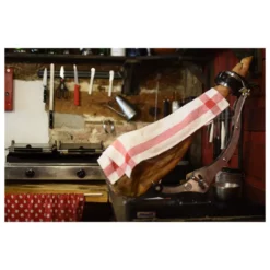 50% Iberico ham leg on a support covered with a towel in a kitchen