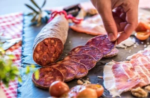 Acorn-fed Iberian Chorizo being places on a charcuterie board